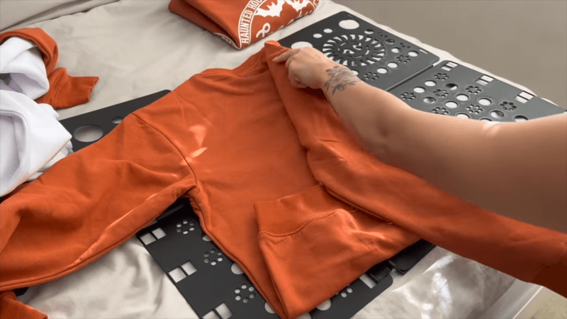 an orange embroidered sweatshirt being folded