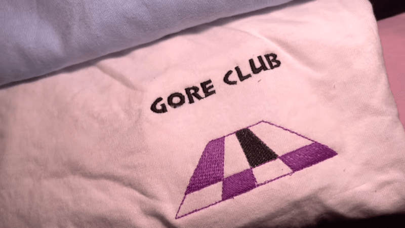 a pink embroidered sweatshirt with gore club text