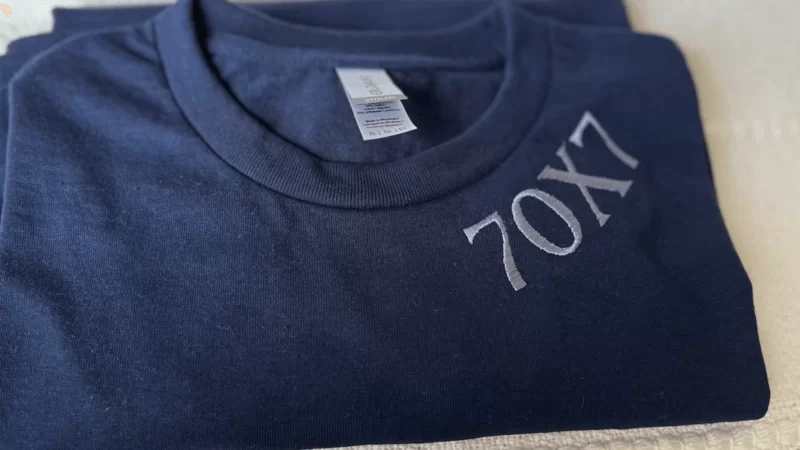 a blue sweatshirt with 70x7 text on the collar