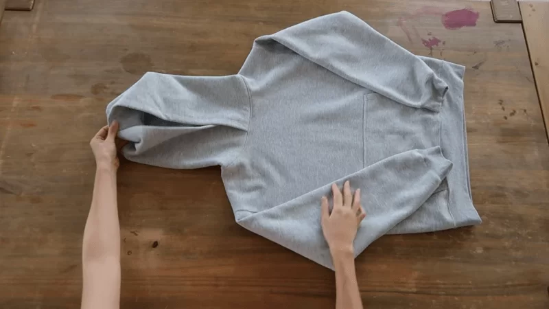 grey hoodie is being folded by person